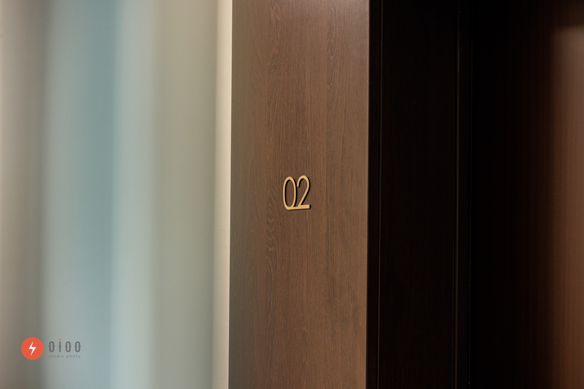 Photographie immobilière pour le groupe Lamotte à bordeaux par Oioo studio : vue d'un numéro d'appartement doré, apposé sur un mur en bois foncé